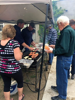 Eric Trojanowski, safety committee member (center left), and Tad Kingsbury, safety committee member (center right), grill burgers and hot dogs for lunch. Lisa Pierson, ARC assistant service manager (far left) helps while Norman James, Project RoadSafe project manager, waits for his burger.